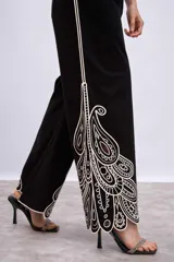 Pantalón blanco de corte ancho con bordados calados en forma de hojas en el ruedo.