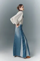 Falda larga acampanada de denim rígido con diseño patchwork en distintos tonos de azul y ruedo desflecado.