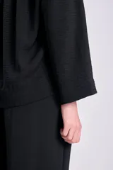 Blusa negra de manga larga con cuello en V y cierre con botones.