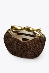 Bolso mini trenzado color marrón con asa de mano dorada metálica y doble asa bandolera ajustable y extraíble. Tiene forro, bolsillo interior y cierre mediante cremallera.