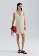 Vestido corto color crema, de corte recto y escote en V.