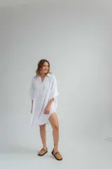 Vestido blanco de lino, corte holgado, con cuello camisero, mangas 3/4 y aberturas laterales.
