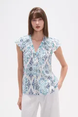 Blusa de rayón con estampado floral en tonos azules y celestes sobre fondo blanco. Presenta cuello en V, botones frontales y mangas cortas con frunces en los hombros.