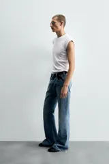 Pantalón de jean celeste, de tiro medio, corte ajustado en la parte superior y acampanado desde la rodilla. Tiene cinco bolsillos, efecto lavado y bajo irregular.