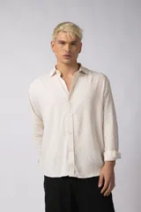 Camisa color crema de lino con caída liviana y calce relajado, cuello abierto y manga larga.