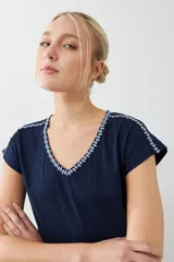 Remera blanca de algodón con escote en V y bordado en el borde. De corte recto y mangas cortas.