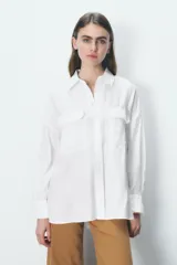 Camisa rosa claro confeccionada en hilatura con modal, de corte holgado, con cuello solapa, manga larga terminada en puño, dos bolsillos con solapa en el delantero y cierre frontal con botones.