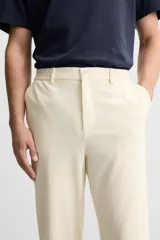 Pantalón color crudo de tejido con textura de rizo, corte relaxed fit, con cintura elástica, bolsillos frontales y traseros, cierre frontal con cremallera y botón.