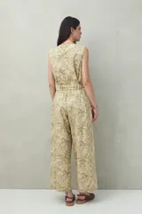 Mono enterito de algodón con rayas verticales color verde claro y beige, con cuello en V, sin mangas, con cierre frontal con botones y cinturón de lazo.