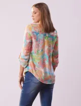 Blusa de gasa estampada con rayas verticales en tonos celeste, azul y blanco. Tiene cuello a la base con escote en V y abertura con botones. Las mangas largas son de largo regulable.