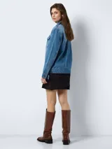 Chaqueta de jean celeste de corte recto con cuello solapa, cierre frontal con botones metálicos, bolsillos de parche con solapa abotonada en el pecho y bolsillos laterales.