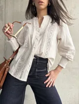 Camisa color beige de lino con detalles de broderie en el frente y mangas largas con puños elásticos.