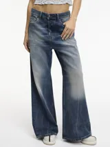 Pantalón de jean de tiro medio con pierna ancha, color azul con efecto desgastado y roturas en la parte delantera.