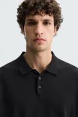 Polo de manga larga color negro, tejido en hilatura con mezcla de algodón y seda, de corte regular fit, con cuello solapa y cierre frontal de botonadura.
