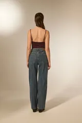 Pantalón jean color natural de calce alto y corte recto, con bolsillos y detalles de strass dispersos por las piernas.