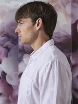 Camisa de manga larga color rosa con rayas verticales blancas, cuello clásico y bolsillo en el pecho. Cierre frontal con botones.