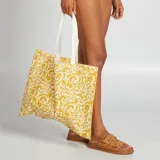 Bolso tipo tote bag grande, color beige con estampado floral en amarillo mostaza y asas de algodón crudo.