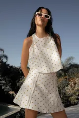 Conjunto de lino blanco con lunares dorados, compuesto por top sin mangas con volado y falda corta con cierre lateral.