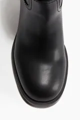 Botines de color negro con punta redonda y taco cuadrado medio. Presentan una trabilla en la parte posterior y costuras decorativas tonales.