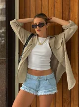 Short de jean de tiro bajo, color celeste claro lavado, con terminación deshilachada en el ruedo y roturas sutiles. Presenta costuras visibles en contraste y corte ajustado.