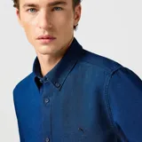 Camisa de manga larga azul índigo de denim con cuello abotonado y logo bordado en el pecho.