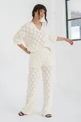 Pantalón de tejido de punto color crema, de tiro alto y pierna ancha, con diseño calado de rombos.