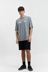 Remera gris de manga corta con corte oversize, cuello redondo y estampado frontal con los logos de Mistral y Excess Streetwear.