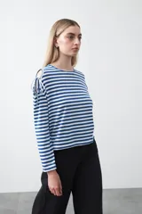 Remera de manga larga a rayas horizontales blancas y negras, con escote redondo y aberturas en los hombros sujetas con lazos regulables de tela a rayas.