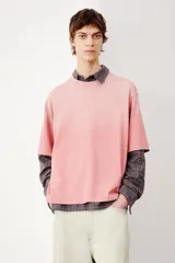 Remera rosa con efecto desteñido, corte amplio, cuello redondo y mangas cortas.