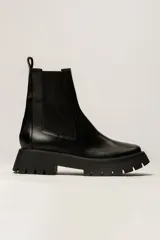 Botas Chelsea negras de cuero con elástico lateral y suela track.