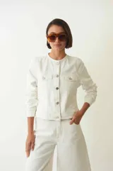 Campera de pana color blanco con cuello a la base, abotonada en el frente, entallada al cuerpo, fit corto y con dos bolsillos en la delantera.