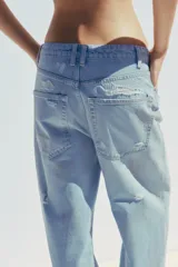 Pantalón de jean celeste claro, corte baggy, tiro medio, largo hasta el tobillo y con roturas grandes en ambas piernas.
