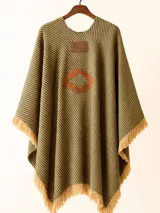 Ruana con diseño a rayas verticales en tonos beige y marrón, con flecos en el borde inferior y aplique de cuero con el logo de la marca en el pecho.