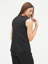 Chaleco sastre negro, sin mangas, con escote en V profundo y cierre frontal de botones. Presenta un bolsillo superior simulado en el lado izquierdo.