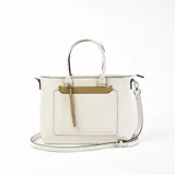 Cartera tipo tote de cuero sintético color blanco con bolsillo externo marrón con cierre. Tiene doble asa de mano y correa larga desmontable y regulable.