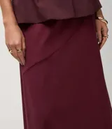 Pollera midi evasé color vino tinto, confeccionada en bengalina. Presenta un recorte horizontal en la parte delantera.