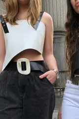 Top corto de ecocuero blanco con breteles anchos de ecocuero negro con textura de cocodrilo y hebillas metálicas.