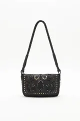 Cartera bandolera de cuero vacuno color negro, con correa trenzada y solapa con diseño calado y tachas. Incluye pañuelo estampado atado al asa.