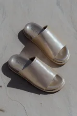 Sandalias planas negras tipo slide, con capellada ancha de pelo corto. Tienen suela de caucho expandido y base plana de 3 cm de altura.