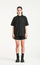 Camisa negra de manga corta con textura y cuello clásico.
