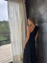 Vestido largo negro de un solo hombro, confeccionado en tela tableada con sutiles brillos.