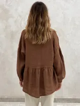Blusa marrón de lino con escote en V, mangas largas abullonadas y detalle de encaje en la parte inferior.