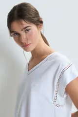Conjunto de pijama blanco de algodón, compuesto por una remera de mangas cortas con cuello en V y detalle de calado en los bordes, y un pantalón largo de corte recto con calado en el ruedo.