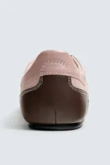 Zapatillas deportivas de piel color rosa con detalles en marrón en la parte trasera. Cierre con cordones al tono.
