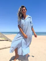 Vestido camisero largo celeste con rayas verticales blancas, cuello camisero, mangas cortas con trabilla y botones, cierre frontal con botones y bolsillos laterales.