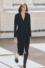 Vestido midi negro de escote pico y manga larga con hombreras. Tiene falsos bolsillos de vivo en el delantero y cierre en la espalda con cremallera oculta.
