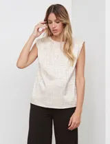 Blusa de gasa color beige con textura labrada, sin mangas, con hombreras internas y abertura en la espalda con botón.