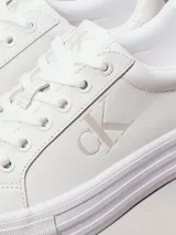 Zapatillas urbanas Calvin Klein Jeans de cuero sintético color blanco, con plataforma plana, cordones y logo CK en el lateral.