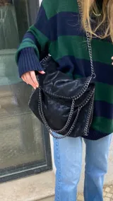Bolso tote negro con textura arrugada y detalles de cadena plateada en las asas y los bordes.