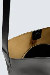 Bolso tipo shopper negro fabricado en piel, con asa de hombro y cierre magnético.